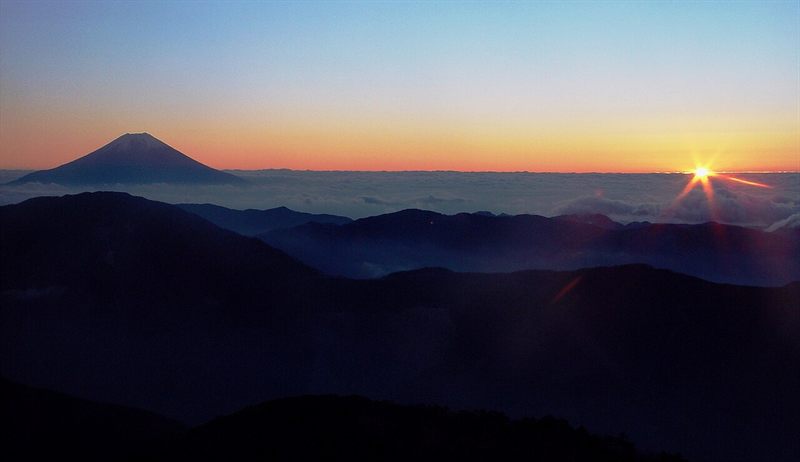 Mount Fuji and layered mountain ridges rising from a sea of clouds at sunrise
